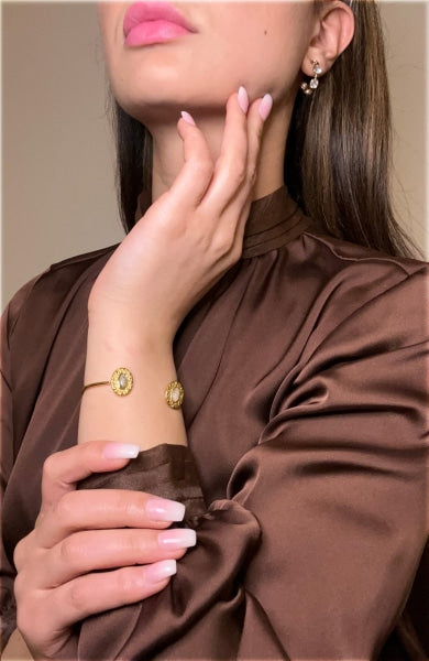 Grey and light brown oval pearls hoop bracelet on wrist.